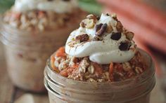 two jars filled with food sitting on top of a wooden table next to carrots