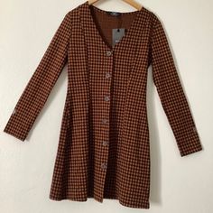 New Bershka Bsk Brown/Black Long Sleeve Dress. Size Usa M Eur M Mex 28. 44% Cotton 40% Polyester 14% Viscose 2% Elastane. Brown V-neck Mini Dress With Buttons, Trendy A-line Mini Dress For Fall, Casual Brown Winter Dress, Brown Midi Dress With Button Closure For Work, Plaid V-neck Winter Dress, Winter Plaid V-neck Dress, Chic Brown Dress With Buttons, Long Sleeve Mini Dress With Button Closure For Fall, Chic Brown Dresses With Button Closure