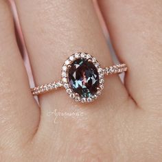 a woman's hand holding a ring with a brown and white diamond in it