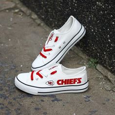 a pair of white shoes with the word chiefs painted on them sitting next to a wall