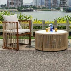 two wicker chairs and a table with drinks in front of a body of water