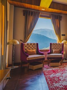 a living room filled with furniture and a large window overlooking the mountain range in the distance