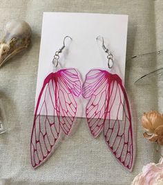 the earrings are made out of wire and have pink leaves on them, along with seashells