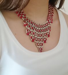 a woman wearing a red and gold necklace with matching earrings on her left shoulder,