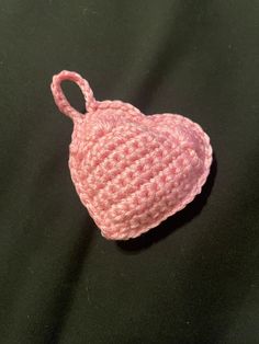 a pink crocheted heart ornament on a black surface