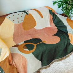 a couch covered in a colorful blanket next to a potted plant