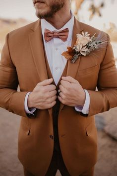 a man in a brown suit and bow tie with flowers on his lapel collar