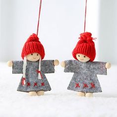 two little dolls hanging from strings in the shape of people with red hats and scarfs