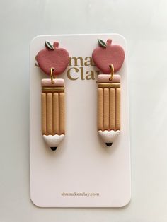 the earrings are made out of wood and have an apple on top with pencils attached to them