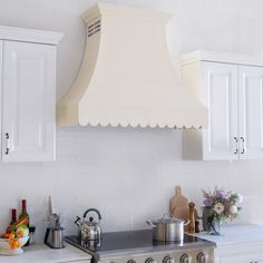 a stove top oven sitting inside of a kitchen next to white cabinets and cupboards