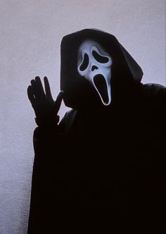 a person wearing a ghost mask and holding their hands up to the side with his mouth open