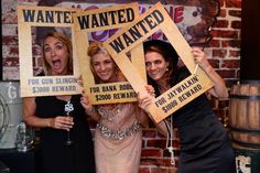 three women holding up wanted wanted signs in front of a brick wall at a party