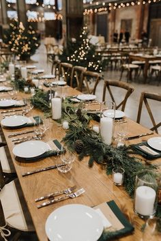 a long table with place settings and candles on it in a large room decorated for christmas