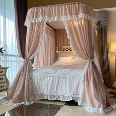 a canopy bed with pink drapes on it's headboard and foot board