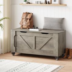 a wooden storage box sitting on top of a floor next to a rug and potted plant