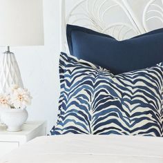 a blue and white pillow sitting on top of a bed next to a night stand