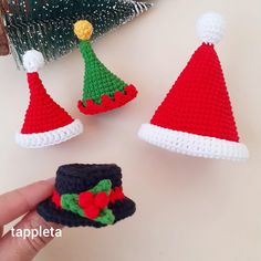 three crocheted christmas hats are shown on a table next to a handmade ornament