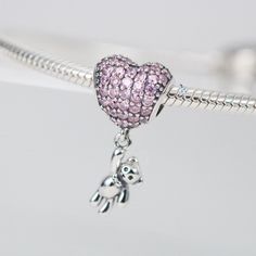 This is charm only, bracelet is sold separately. Bring some extra joy and sparkle to your Valentine's Day with this exquisite heart and teddy bear combo charm. Perfect for adding to a bracelet or necklace, this solid 925 sterling silver charm features a dazzling pink cubic zirconia pave heart and a tiny teddy bear for a touch of cuteness. Show your love with this adorable charm, plated with shiny platinum to keep it shining for years to come. Materials: 925 sterling silver, cubic zirconiaFinish: platinum plateDimensions: 0.82 x 0.42 x 0.30 inHole size: 0.18 in Jewelry Care: See more information about how to care for your jewelry here. Shipping Policy: Orders will be shipped within 1-3 business days. Economy shipping will take 7-14 days to arrive and standard shipping is 1- 4 days for U.S. Pink Sterling Silver Dangle Charms, Cubic Zirconia Charm Bracelet Gift, Silver Heart Charms For Birthday, Silver Heart Charm For Birthday, Pink Heart-shaped Jewelry With Dangling Charms, Pink Heart Pendant Charms As Gift, Sterling Silver Heart Charms With Dangling Details, Pink Heart-shaped Dangling Charms, Silver Pendant Charms With Cubic Zirconia