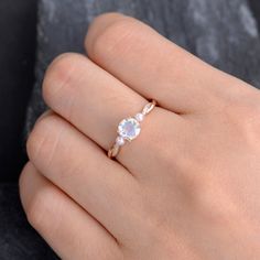 a woman's hand with a diamond ring on her left hand and the other hand holding an engagement ring