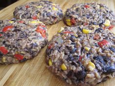 four hamburger patties on a cutting board with corn and tomatoes in the middle, ready to be eaten