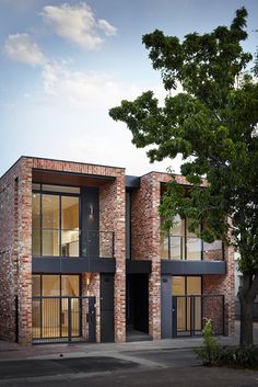 an image of a brick building with glass doors and windows on the outside, in front of a tree