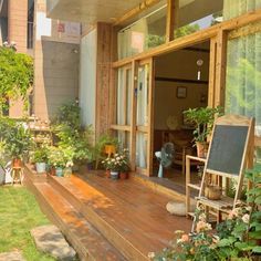 a wooden deck with potted plants on it and a chalkboard in the window