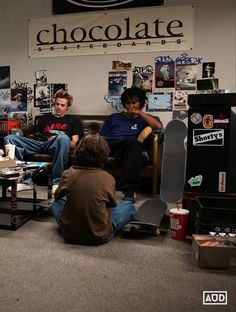 three people sitting in a room with skateboards