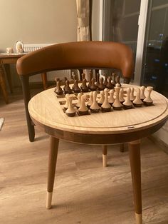 a wooden chess set sitting on top of a table next to a brown leather chair