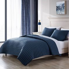 a bed in a bedroom with blue and white comforters