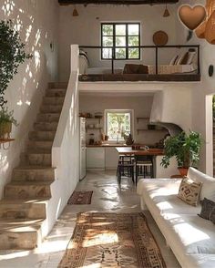 a living room filled with furniture next to a staircase leading up to a loft bed