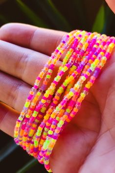 there is a hand that has some bracelets on it, and the beads are multicolored