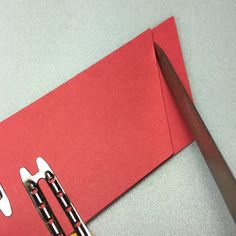 a pair of scissors sitting on top of a piece of red paper next to a knife