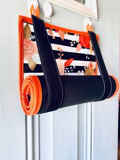 an orange and black purse hanging on a white door