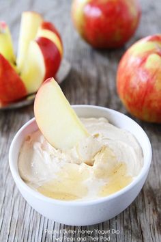 an apple dip in a white bowl with apples around it on a wooden table top