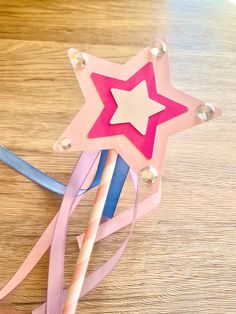 a paper star on top of some pink and blue streamers next to pencils