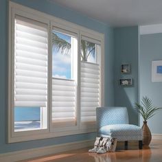 an empty living room with blue walls and white shutters on the window sill