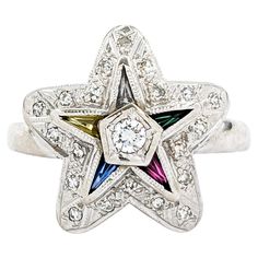 Vintage Eastern Star Diamond & Gemstone Ring Introducing this exquisite vintage Eastern Star Ring, crafted in 14k white gold. This stunning piece features a .25ctw round diamond centerpiece surrounded by multi-tapered gemstones (synthetic Ruby, Sapphire & Emerald) and natural diamonds. The Eastern Star symbol, significant for its representation of the principles of fidelity, constancy, loyalty, faith, and love, adds a unique and meaningful touch of history to this elegant ring. The sparkling .25 White Multi-stone Diamond Cluster Ring, White Diamond Multi-stone Cluster Ring, Vintage Star-shaped Anniversary Rings, Vintage White Gold Multi-stone Diamond Ring, Vintage Multi-stone Diamond Ring In White Gold, Dazzling Multi-stone White Diamond Ring, Dazzling White Multi-stone Diamond Ring, Vintage Multi-stone Diamond White Rings, Silver 14k White Gold Multi-stone Diamond Ring