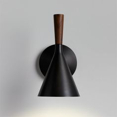 a black wall light with a wooden stick hanging from it's side and a white background