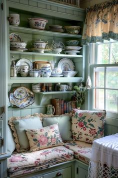 a room filled with lots of furniture and plates on top of green shelves next to a window