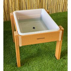 a wooden table with an ice chest on it in the grass next to a bamboo wall