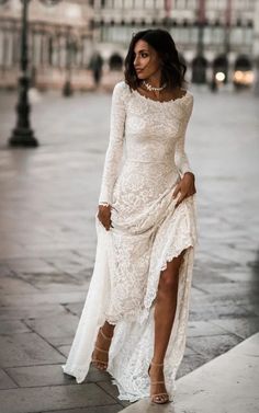 a woman in a white dress is walking down the street