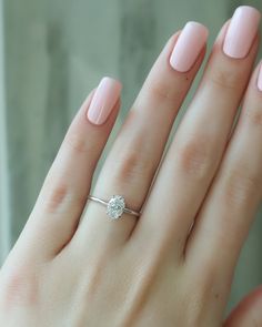 a woman's hand with a pink manicured nail polish holding a diamond ring