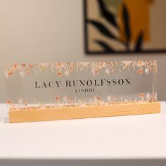 a business card sitting on top of a white table next to a vase with flowers