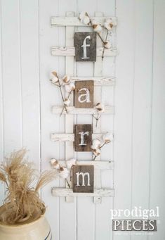 a wooden sign that says farm on it next to a potted plant and a white wall