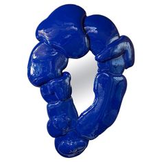 a blue sculpture is shown in front of a white background with the reflection of it's hands