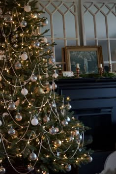 a decorated christmas tree in front of a fireplace