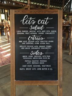 a blackboard sign with some writing on it in front of a table and chairs