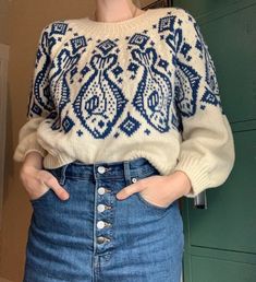 a woman wearing a blue and white sweater is standing in front of a green door