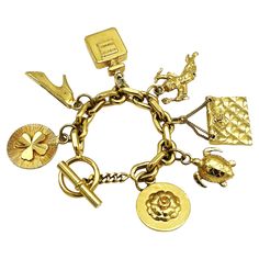 Chanel's gold-tone chain link bracelet with seven iconic Chanel items hung from the chain such as a shamrock, heels, a perfume bottle, cupid, a quilted Chanel bag and a turtle, a camellia, Coco Chanel's favorite flower! All iconic charms are almost identical on both sides and 24k gold plated. Measurement: The bracelet has a length of 20 cm, Size of the charms, the quilted pocket 3.5 x 2.5 cm, perfume bottle 3.5 x 2.5 cm, camelliar 3 cm, locking ring 2 cm, toggle 3.5 cm Features: - Material solid and gilded, - Signed 'CHANEL' on the clasp ring through which the toggle is inserted. - 7 iconic Chanel charms. - Excellent vintage condition - Luxury Vintage Gold Charm Bracelet, Chanel Charms, Chanel Items, Quilted Pocket, Chanel Pendant, Lucky Charm Bracelet, Favorite Flower, Gold Charm Bracelet, Lucky Charm