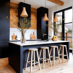 a kitchen with black cabinets and stools next to an island in front of a window